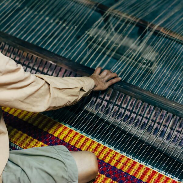 A person is weaving on a loom with a basket